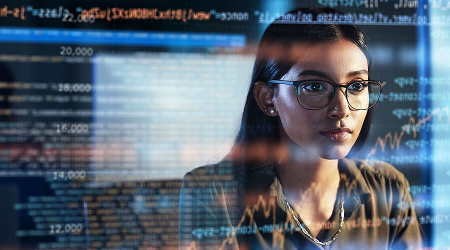 Eine junge Frau spiegelt sich in einem Monitor mit Zahlenkolonnen.