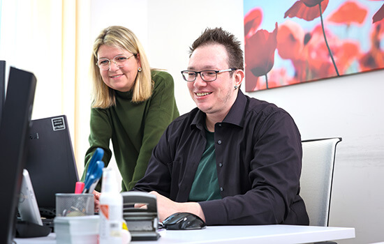 Sonja Kleinert und Alexander Metelmann schauen zusammen auf einen PC-Bildschirm. 