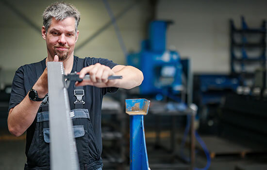 Arbeiter der eine Metallleiste vermisst | © Rupert Oberhäuser Ein Arbeiter vermisst eine Metallleiste in einer Werkstatt.