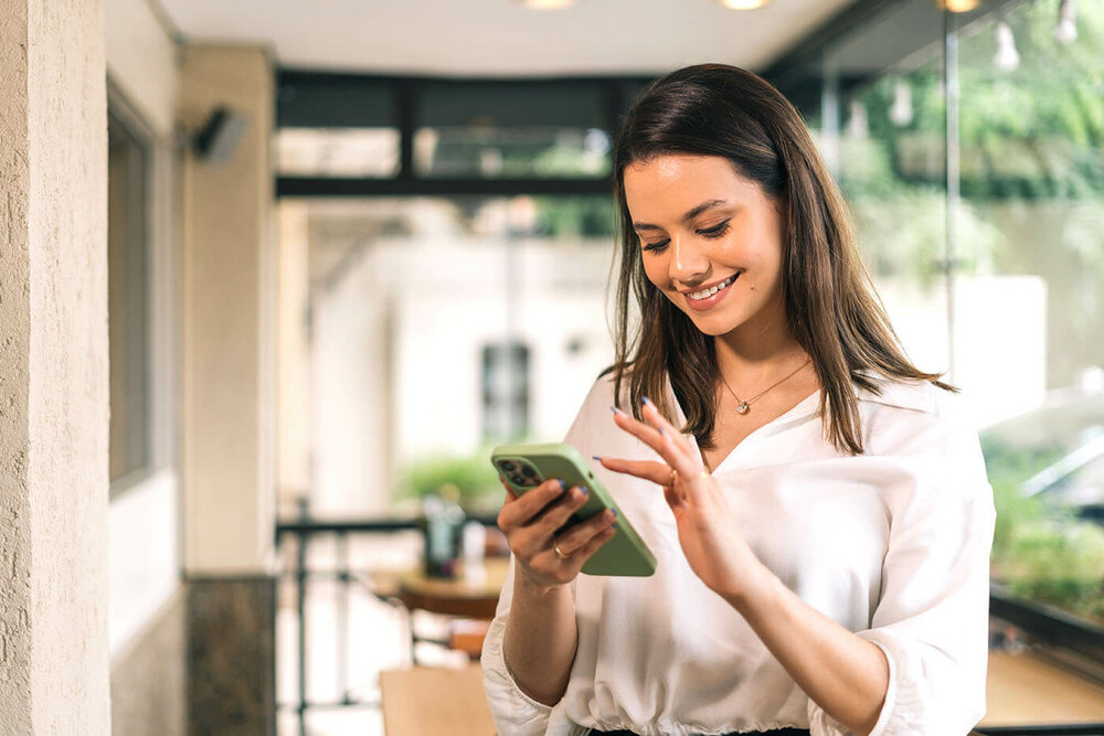 junge Frau schaut lächelnd in ihr Smartphone