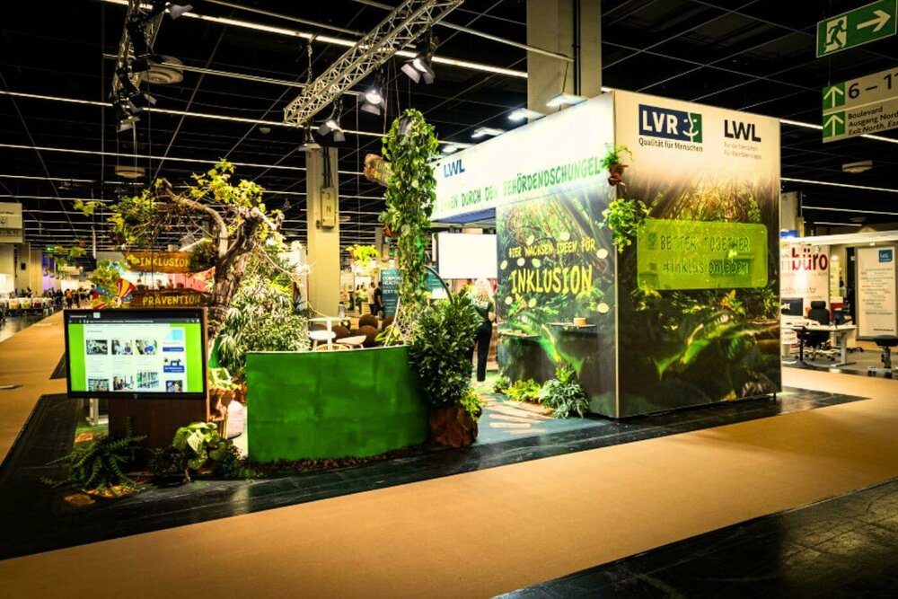 Das Foto zeigt den Messestand von LVR und LWL auf der Messe Zukunft Personal Europe. Der Stand ist mit vielen Pflanzen wie ein Behördendschungel gestaltet.